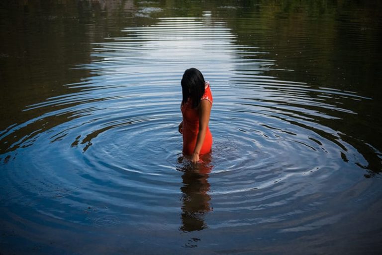 Woman in water wearing red dress with ripples